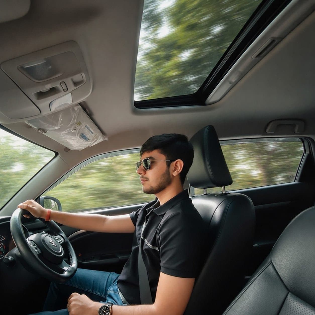 Harshit driving a car, trees blurring past the windows and sunroof
