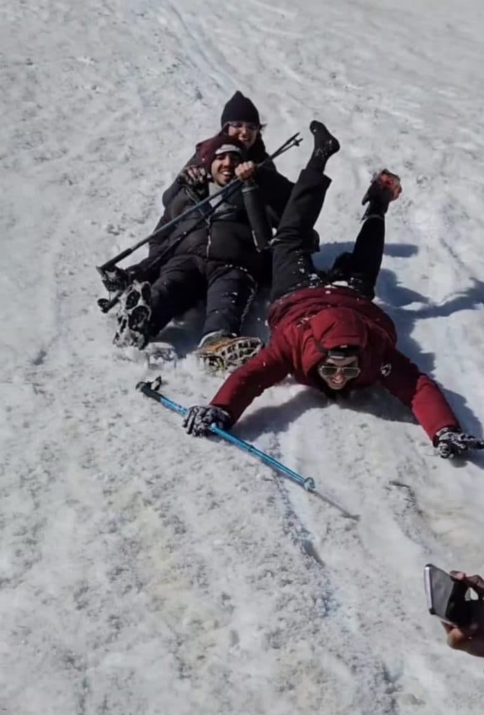 Harshit and friends fallen over laughing in the snow on a trek