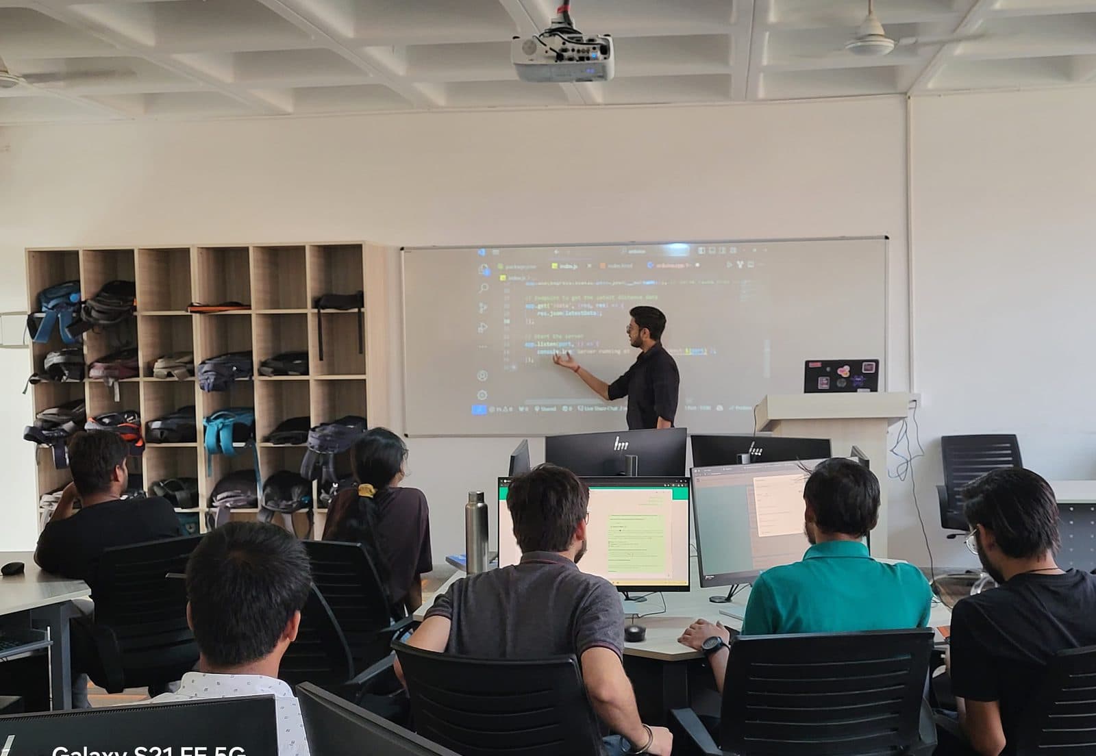 A full computer lab of students watching Harshit explain code on the projector